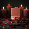 Scarlet Noir goat milk soap bars prominently displayed with rose petals and dried rosebuds in bright, soft natural light