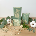 Eucalyptus and cotton goat milk soap bars styled on natural wood with fresh eucalyptus branches, white cotton bolls, and mint sprigs