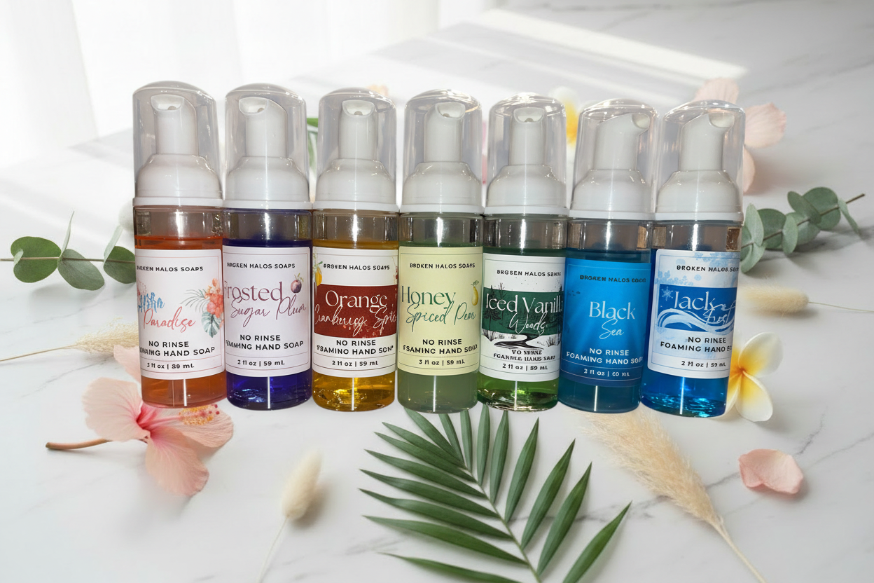 Colorful no rinse foaming hand soap bottles styled on a marble surface with tropical flowers, eucalyptus, and botanicals